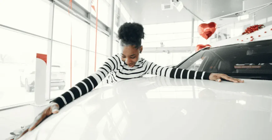 Image showing a lady celebrating her own car, the image shows the cost of owning a car in Dubai