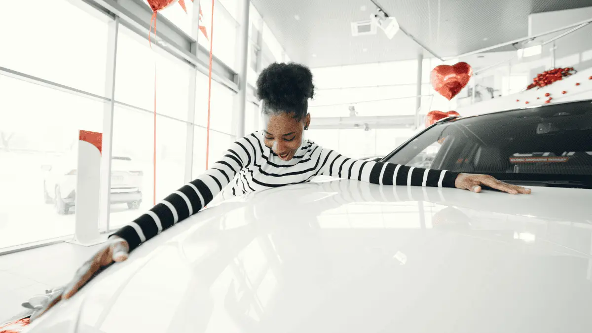 Image showing a lady celebrating her own car, the image shows the cost of owning a car in Dubai